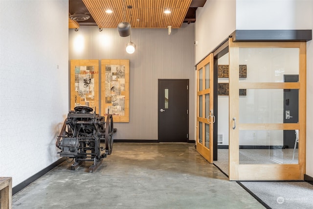 hallway with wood ceiling, french doors, and a high ceiling