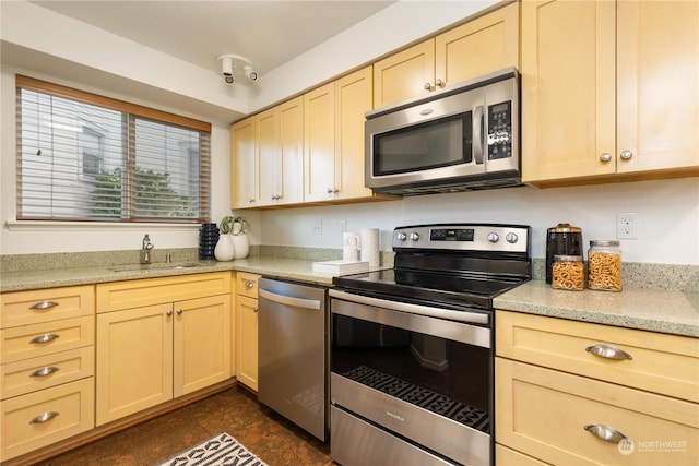 kitchen with stainless steel appliances, sink, light brown cabinets, and light stone counters