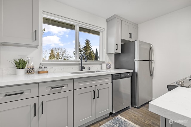 kitchen with dishwasher, sink, dark wood-type flooring, gray cabinetry, and light stone countertops