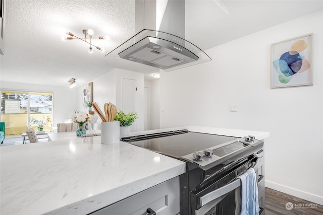 kitchen featuring dark wood-type flooring, stainless steel range with electric stovetop, island exhaust hood, light stone counters, and a textured ceiling