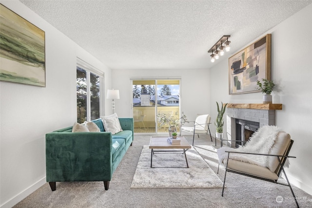 carpeted living room featuring track lighting, a brick fireplace, and a textured ceiling