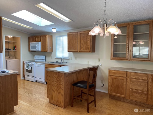 kitchen with pendant lighting, white appliances, light hardwood / wood-style flooring, a breakfast bar, and kitchen peninsula