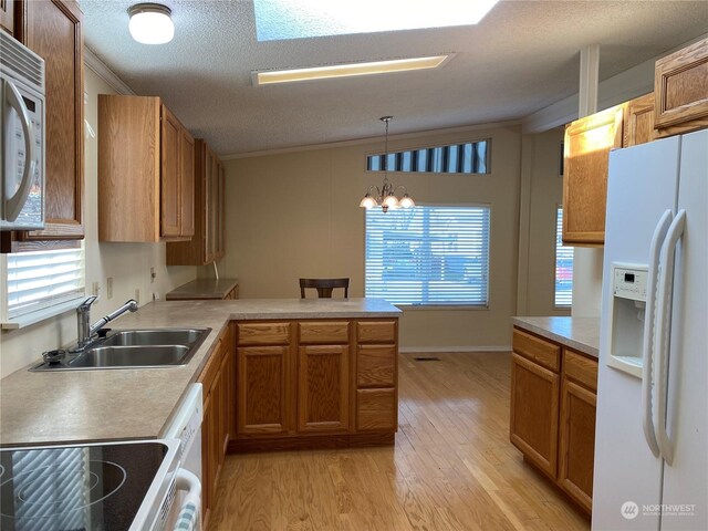 kitchen featuring sink, a textured ceiling, kitchen peninsula, pendant lighting, and white appliances