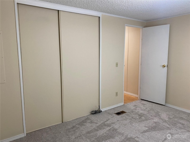 unfurnished bedroom featuring light colored carpet and a textured ceiling