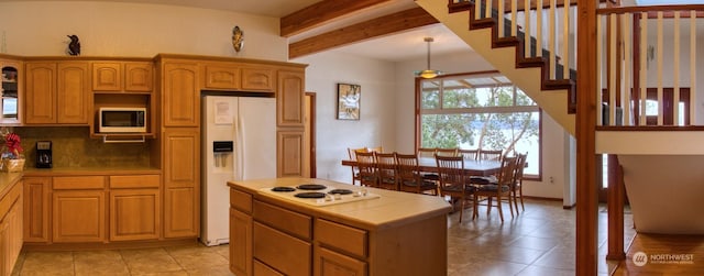 kitchen featuring tile countertops, a kitchen island, white appliances, beam ceiling, and decorative backsplash