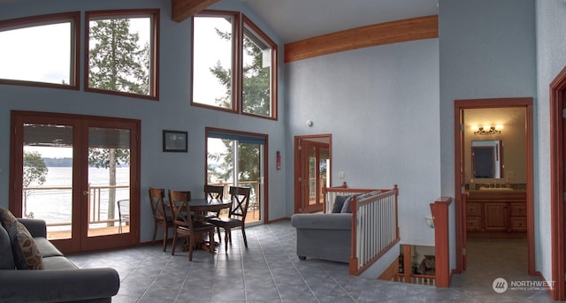 living room with sink, a towering ceiling, a water view, french doors, and beamed ceiling