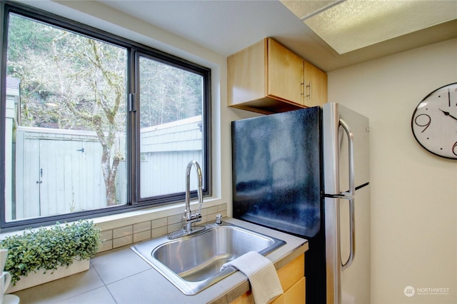 kitchen with sink, light brown cabinets, and stainless steel fridge