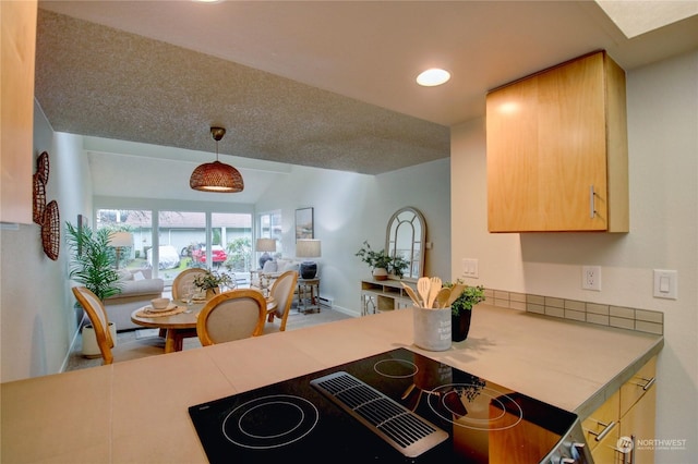 kitchen featuring hanging light fixtures, light brown cabinets, a textured ceiling, and black electric cooktop