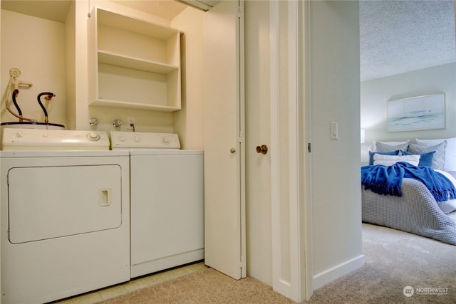 clothes washing area featuring light colored carpet, washing machine and clothes dryer, and a textured ceiling