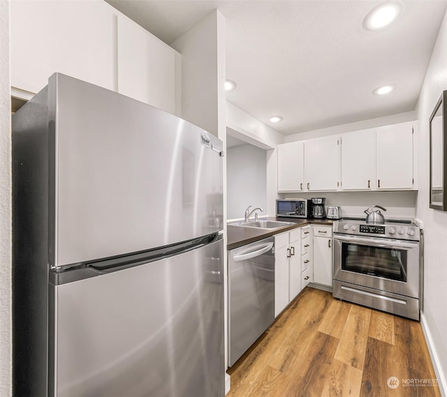 kitchen featuring white cabinetry, stainless steel appliances, light hardwood / wood-style floors, and sink