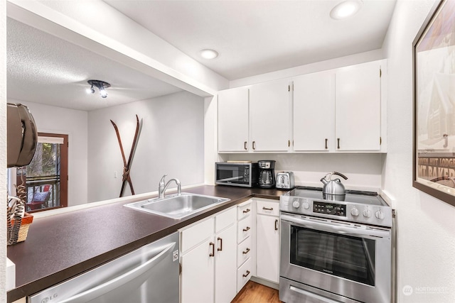 kitchen featuring stainless steel appliances, white cabinetry, sink, and light hardwood / wood-style flooring