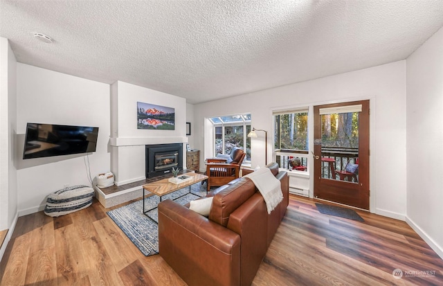 living room with hardwood / wood-style floors, a textured ceiling, and a baseboard heating unit