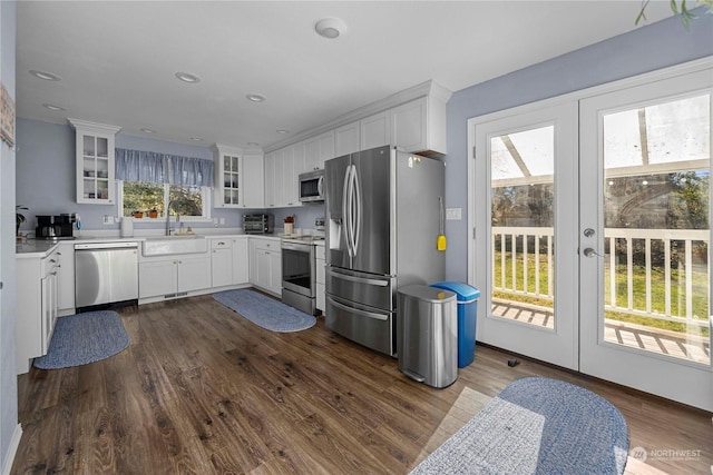 kitchen with appliances with stainless steel finishes, dark wood-type flooring, white cabinetry, french doors, and sink