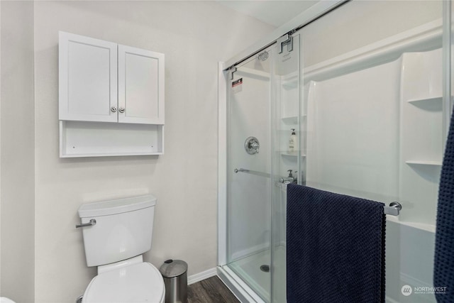 bathroom featuring hardwood / wood-style flooring, an enclosed shower, and toilet