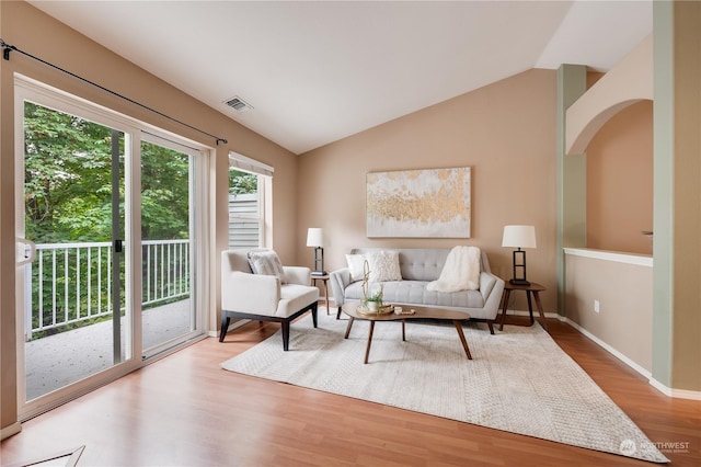 living area featuring lofted ceiling, baseboards, visible vents, and wood finished floors