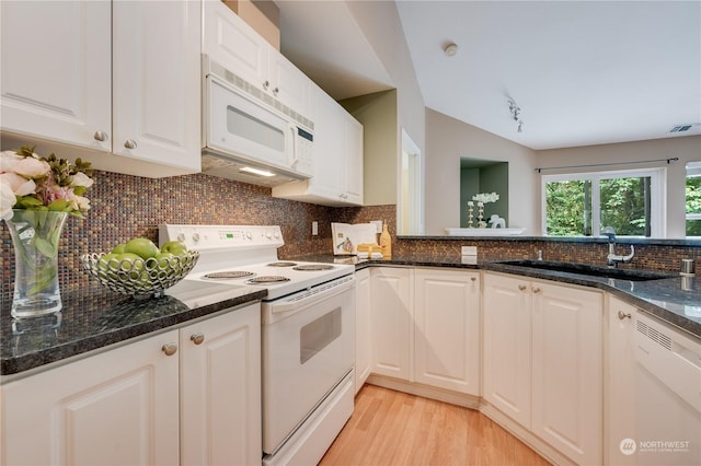 kitchen with white appliances, white cabinetry, dark stone countertops, tasteful backsplash, and sink