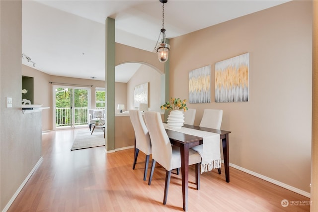 dining area with light hardwood / wood-style floors and vaulted ceiling