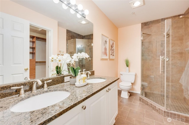 bathroom featuring toilet, tile patterned flooring, a shower with shower door, and vanity