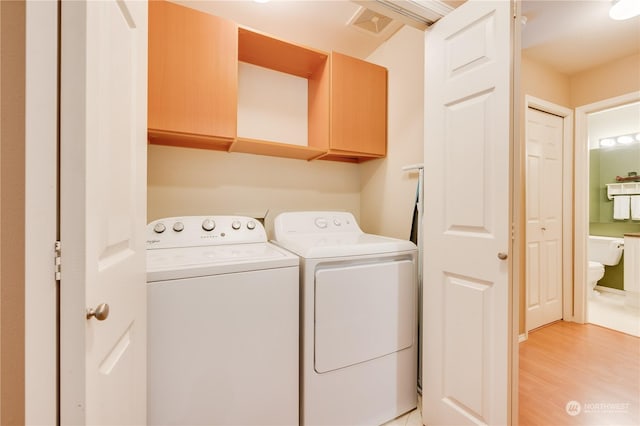 laundry room with cabinets, separate washer and dryer, and light hardwood / wood-style flooring