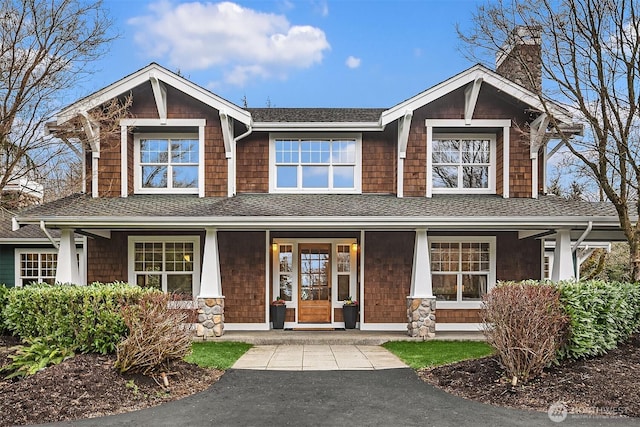 craftsman-style house featuring a porch, roof with shingles, and a chimney