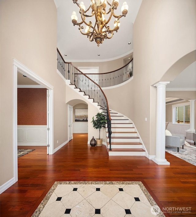 foyer featuring arched walkways, wood finished floors, and decorative columns