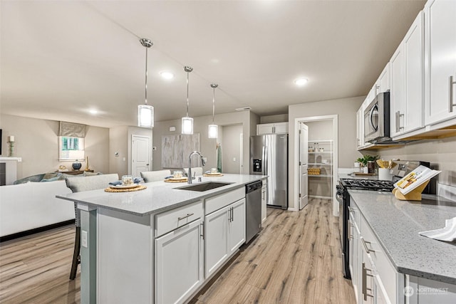 kitchen with pendant lighting, sink, white cabinetry, stainless steel appliances, and an island with sink