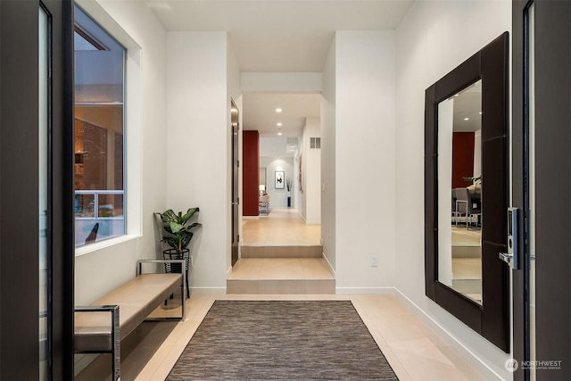 corridor featuring light tile patterned flooring and baseboards