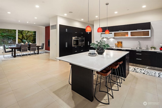 kitchen with light countertops, a sink, visible vents, and dark cabinets