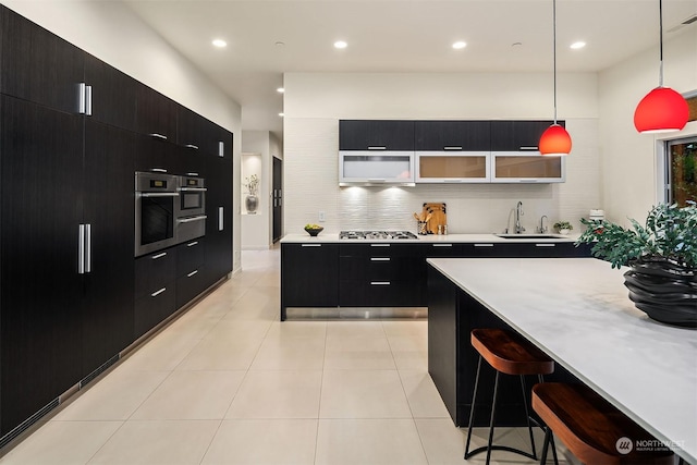 kitchen featuring modern cabinets, appliances with stainless steel finishes, a breakfast bar, dark cabinets, and light countertops
