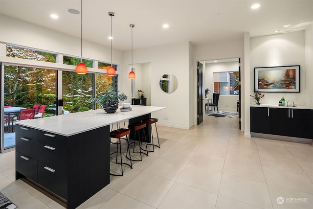 kitchen with dark cabinets, recessed lighting, light countertops, and a breakfast bar area