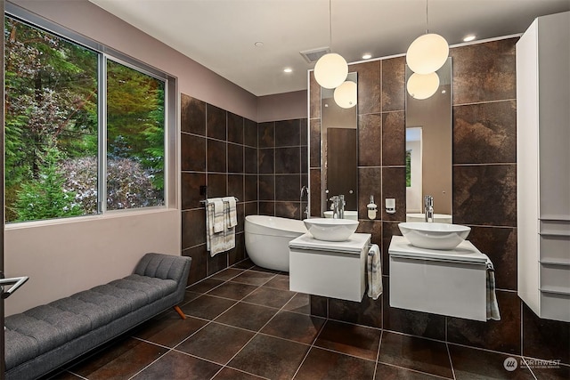bathroom featuring visible vents, a soaking tub, tile patterned flooring, and tile walls