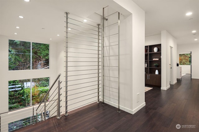interior space with a healthy amount of sunlight, wood finished floors, an upstairs landing, and recessed lighting
