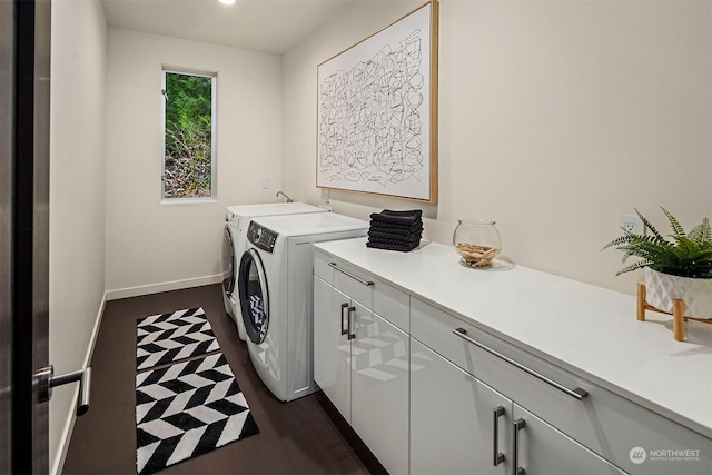 washroom featuring washing machine and dryer, dark wood-style flooring, cabinet space, and baseboards