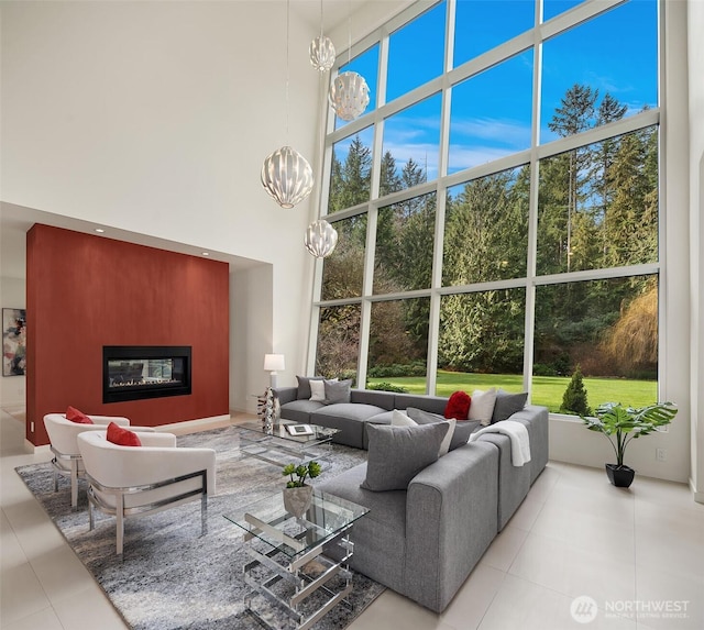 living room with a glass covered fireplace, a notable chandelier, a high ceiling, and tile patterned floors