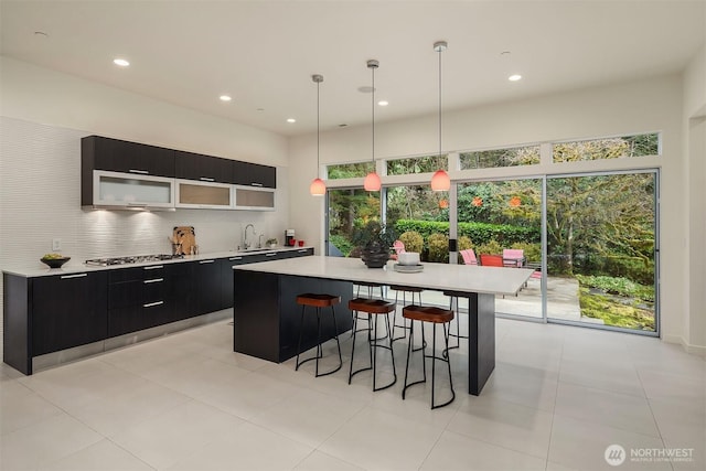 kitchen featuring a breakfast bar, stainless steel gas cooktop, light countertops, modern cabinets, and dark cabinetry