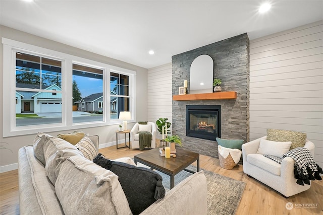 living room featuring a stone fireplace and light hardwood / wood-style floors