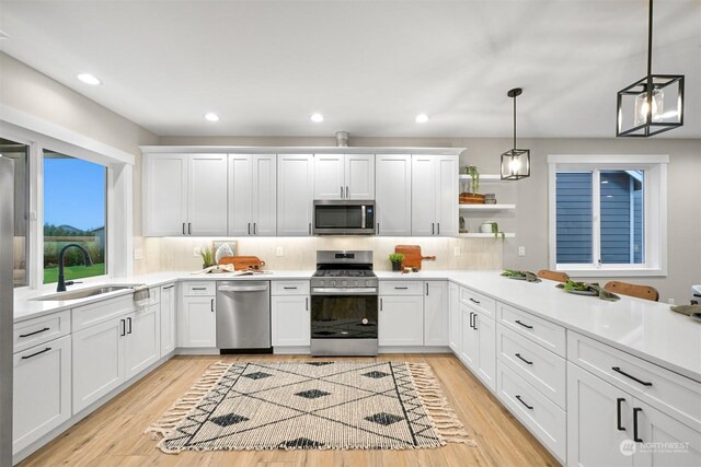 kitchen featuring appliances with stainless steel finishes, sink, hanging light fixtures, and white cabinets