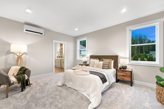 bedroom with an AC wall unit, sink, light carpet, and ensuite bath