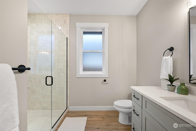 bathroom featuring wood-type flooring, toilet, a shower with door, and vanity