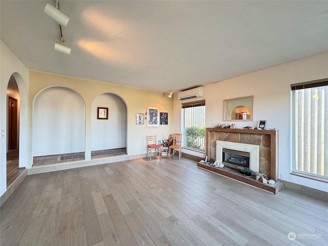 unfurnished living room with track lighting, light hardwood / wood-style flooring, and an AC wall unit