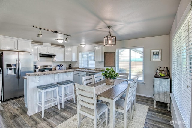 kitchen featuring pendant lighting, a kitchen island, white cabinets, and appliances with stainless steel finishes