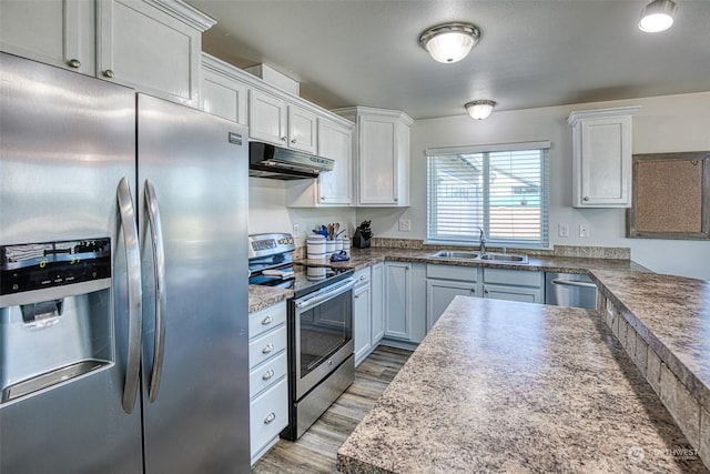 kitchen featuring light wood-type flooring, stainless steel appliances, sink, and white cabinets