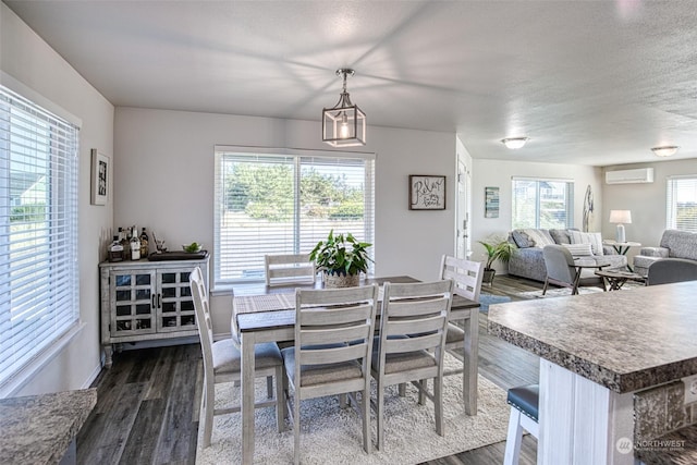 dining area with a textured ceiling, dark wood-type flooring, a wall mounted AC, and plenty of natural light