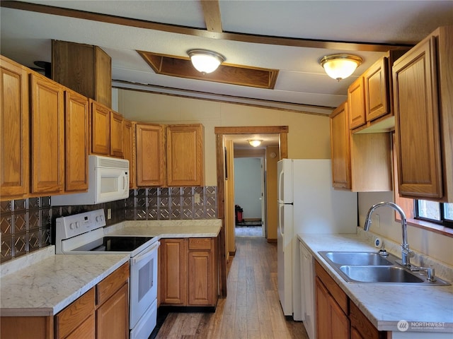 kitchen with white appliances, decorative backsplash, sink, vaulted ceiling, and light hardwood / wood-style flooring