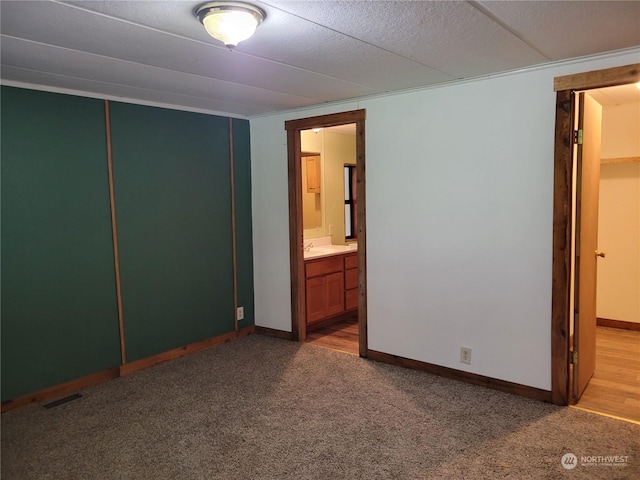 unfurnished bedroom featuring light colored carpet, a closet, and ensuite bath