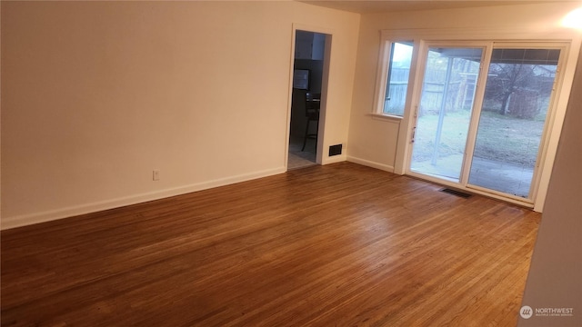 spare room featuring wood-type flooring and plenty of natural light