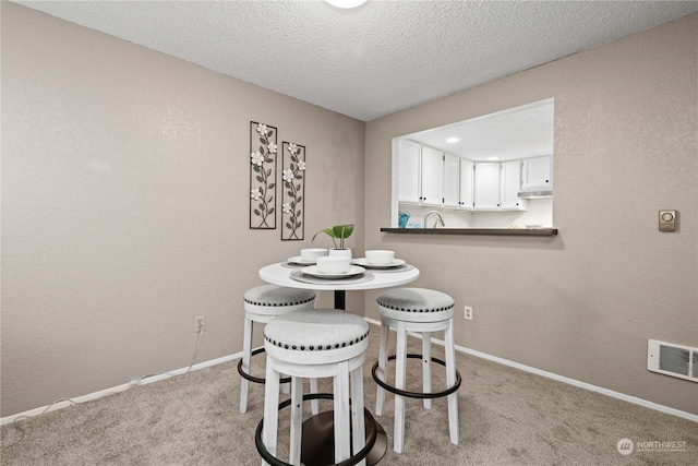 carpeted dining room with a textured ceiling