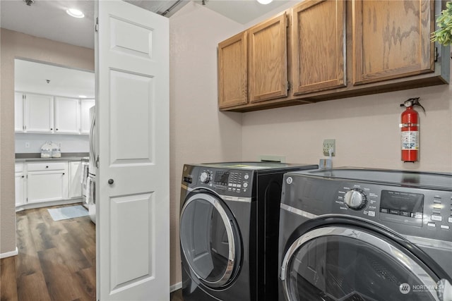 laundry room featuring cabinets, dark hardwood / wood-style floors, and washing machine and clothes dryer