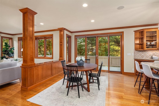 dining space with decorative columns, light hardwood / wood-style flooring, and ornamental molding