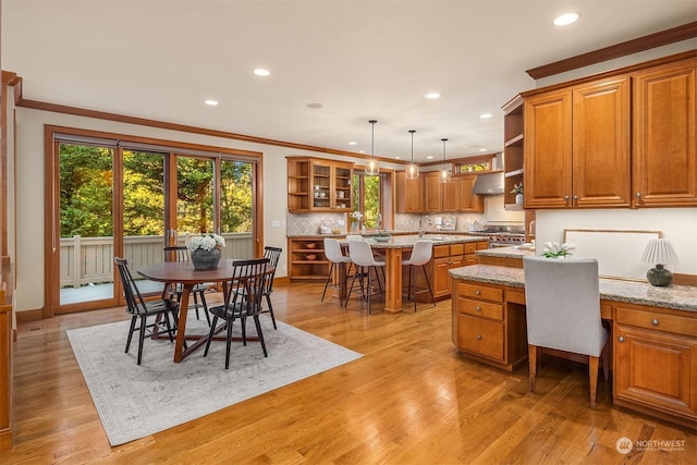 dining space featuring light hardwood / wood-style floors, sink, crown molding, and built in desk